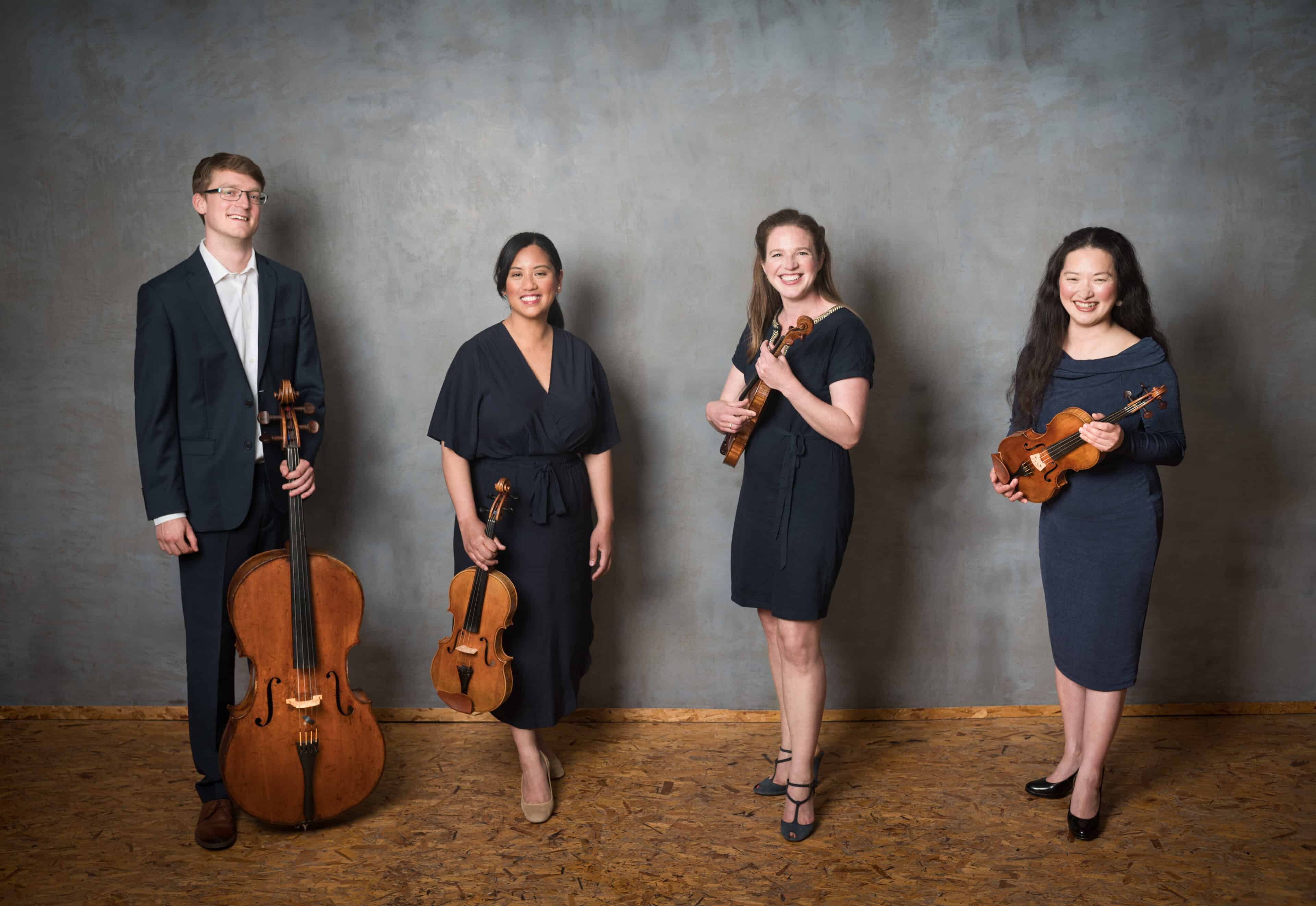The four members of the Villiers Quartet, holding instruments in front of a grey background