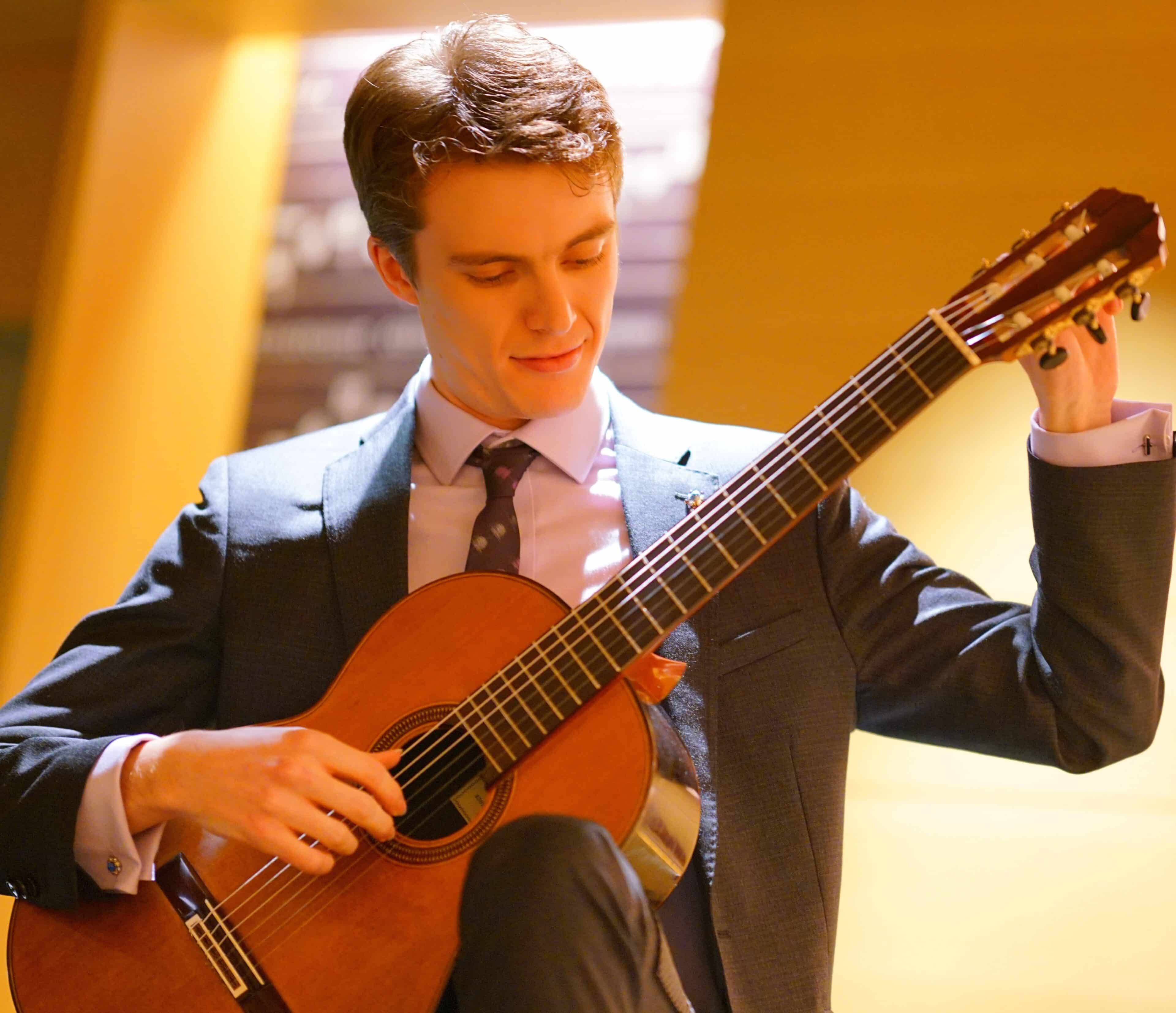 photo of Emmanuel playing the guitar in a yellow room