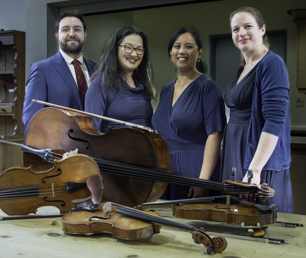 Four members of the Villiers Quartet with their instruments on the table in front of them