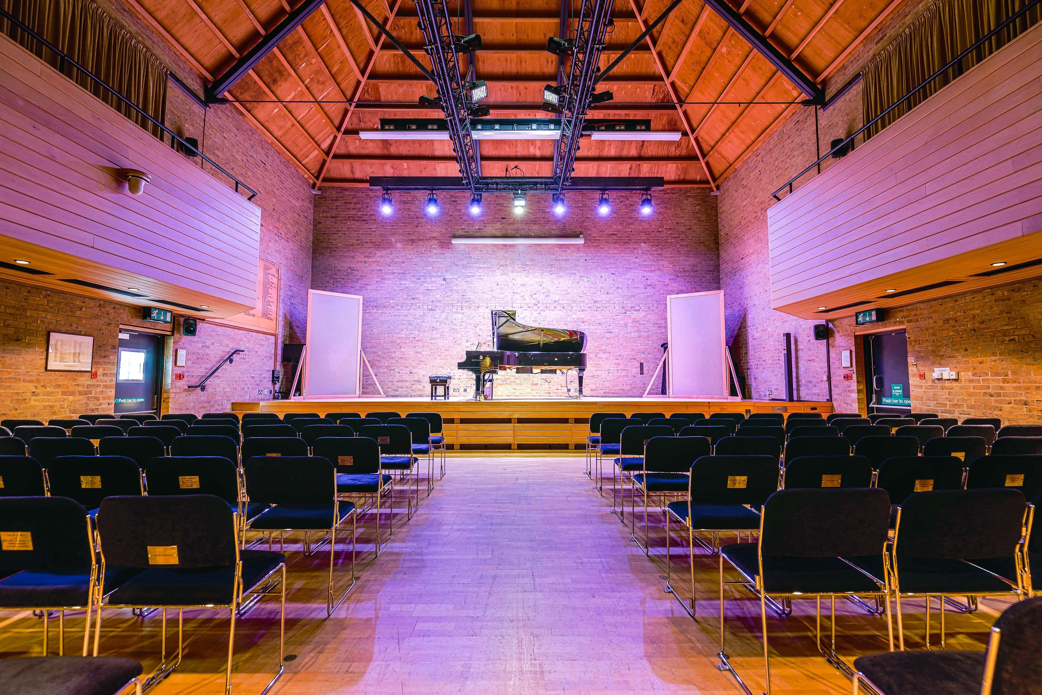 Photo of the JdP stage with piano centre stage. Photo taken from the back of the audience seats near the main entrance so stage is quite far off with audience seats in the foreground